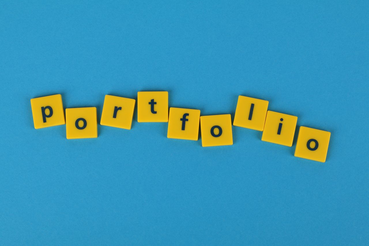 about-us Yellow Scrabble tiles on a blue background spelling portfolio. Perfect for business themes.